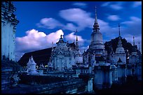 Chedis in blue light with bright clouds, Wat Suan Dok, dusk. Chiang Mai, Thailand (color)