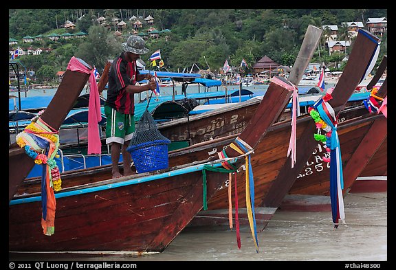 Row of boats, fisherman standing, Ko Phi Phi. Krabi Province, Thailand (color)