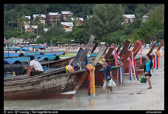 Women returning with shopping bags prepare to board boats, Ko Phi Phi. Krabi Province, Thailand (color)