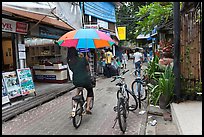 Woman riding bicycle with unbrella, Tonsai village, Ko Phi-Phi Don. Krabi Province, Thailand (color)