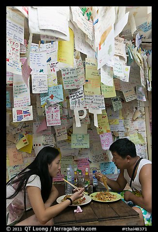 Couple eating Pad Thai below notes of praise left by customers, Ko Phi Phi. Krabi Province, Thailand (color)
