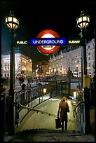 Woman with shopping bag entering subway at night, Piccadilly Circus. London, England, United Kingdom (color)