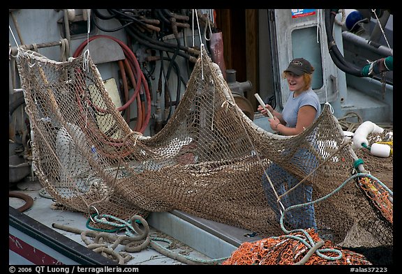 Woman repairing net on fishing boat. Whittier, Alaska, USA