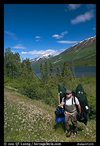 Fisherman hiking out from lake with full gear. Alaska, USA