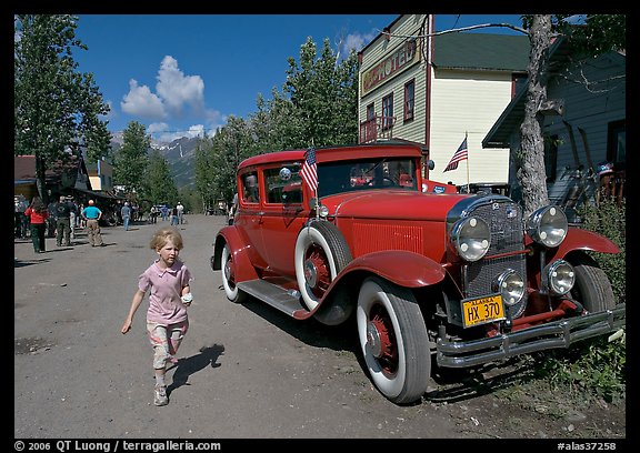 Girl on main street with red classic car. McCarthy, Alaska, USA