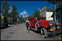 Woman walking next to red classic car. McCarthy, Alaska, USA (color)