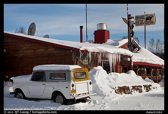 Old truck parked next to lodge in winter. Alaska, USA