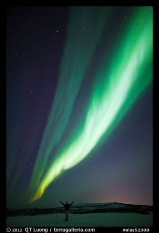 Aurora Borealis streaming above person with outstretched arms. Alaska, USA