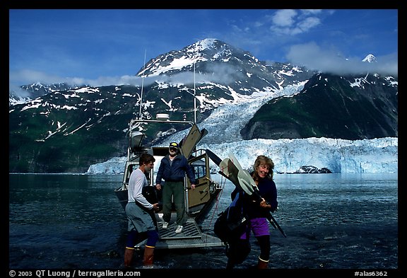 Kayakers unloading kayak from water taxi boat at Black Sand Beach. Prince William Sound, Alaska, USA