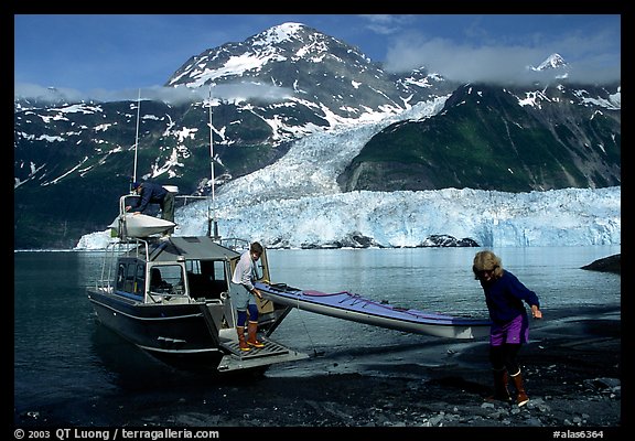 Man and woman  unload  kayak from the water taxi boat at Black Sand Beach. Prince William Sound, Alaska, USA