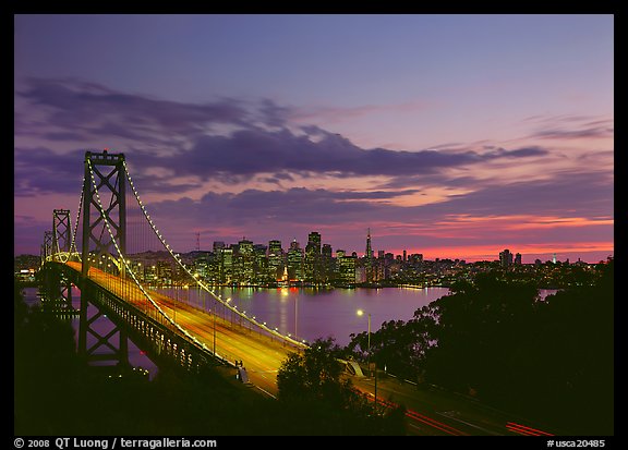 Bay Bridge and city skyline with lights at sunset. San Francisco, California, USA