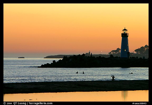 Lighthouse and Surfers in the water at sunset. Santa Cruz, California, USA