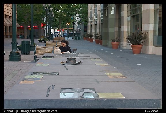 Woman sitting at a commemorative table in a downtown alley. San Jose, California, USA (color)