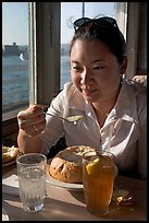 Woman eating a bown of clam chowder on the pier. Santa Cruz, California, USA ( color)