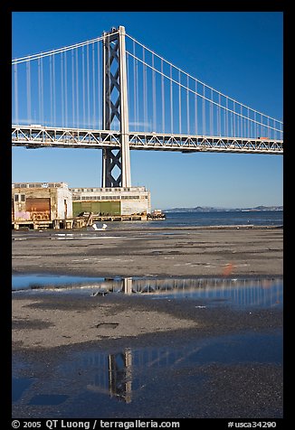 Bay Bridge reflected in water puddles. San Francisco, California, USA