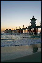 Huntington Pier and reflections in wet sand at sunset. Huntington Beach, Orange County, California, USA