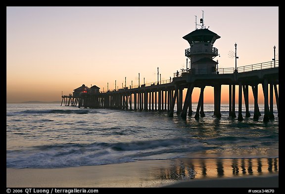 The 1853 ft Huntington Pier reflected in wet sand at sunset. Huntington Beach, Orange County, California, USA