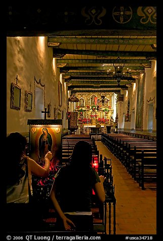 Two women light up candles in the Serra Chapel. San Juan Capistrano, Orange County, California, USA