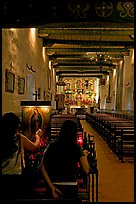 Two women light up candles in the Serra Chapel. San Juan Capistrano, Orange County, California, USA