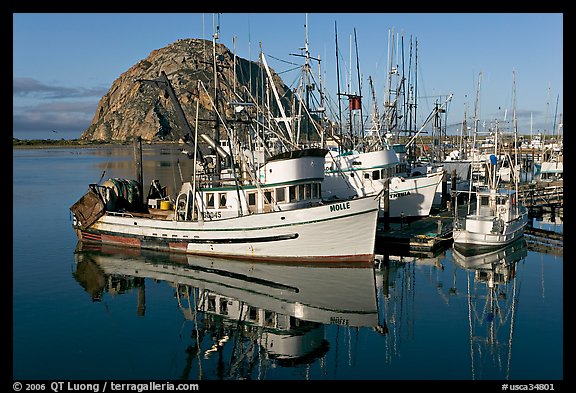 Fishing boats with reflections and Morro Rock, early morning. Morro Bay, USA