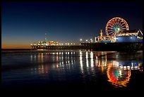 Ferris Wheel and pier reflected on wet sand at night. Santa Monica, Los Angeles, California, USA