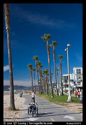 Woman riding a tricycle on the beach promenade. Venice, Los Angeles, California, USA (color)