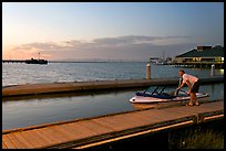 Man holding small boat, Redwood marina, sunset. Redwood City,  California, USA