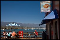 People eating with yachts and beach in background. Santa Barbara, California, USA ( color)
