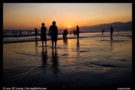People and reflections on beach at sunset, Santa Monica Beach. Santa Monica, Los Angeles, California, USA