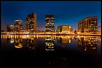 High-rise buildings and Oakland Cathedral reflected in Lake Meritt at night. Oakland, California, USA