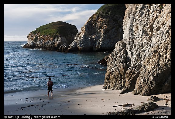 Boy standing at the base of bluff, China Cove. Point Lobos State Preserve, California, USA (color)