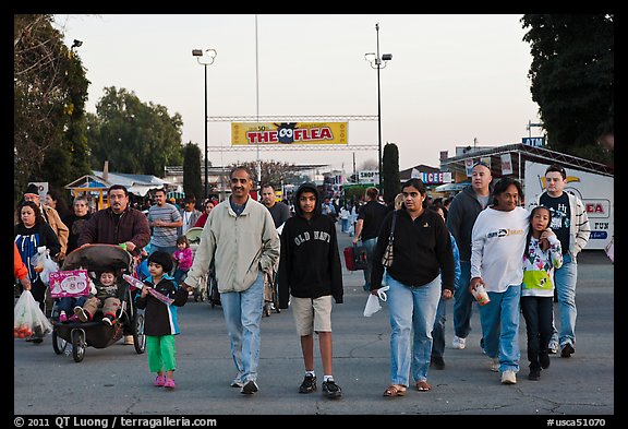 Families walking with entrance sign behind, San Jose Flee Market. San Jose, California, USA