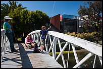 Boy fishing from arched bridge, Venice Canal Historic District. Venice, Los Angeles, California, USA ( color)