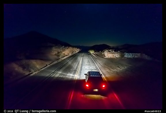 Aerial view of car shining headlights on highway 66 maker at night. Mojave Trails National Monument, California, USA