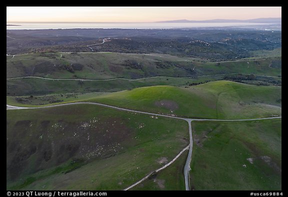 Aerial view of roads, gently rolling hills, with Pacific Ocean in the distance. California, USA