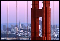 The city seen through the cables and pilars of the Golden Gate bridge, dusk. San Francisco, California, USA (color)
