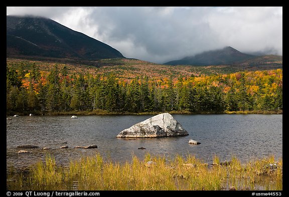 Boulder, pond, forest in autumn and mountains with clouds. Baxter State Park, Maine, USA