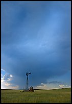 Windmill and tractor under a threatening stormy sky. North Dakota, USA