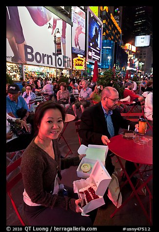 Woman with cupcakes sitting on Times Squares at night. NYC, New York, USA