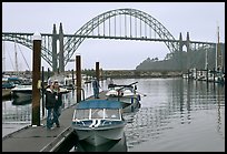 Couple holds  small boat on pier, Newport Marina. Newport, Oregon, USA (color)