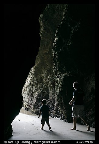 Father and son walking towards the light in sea cave. Bandon, Oregon, USA (color)