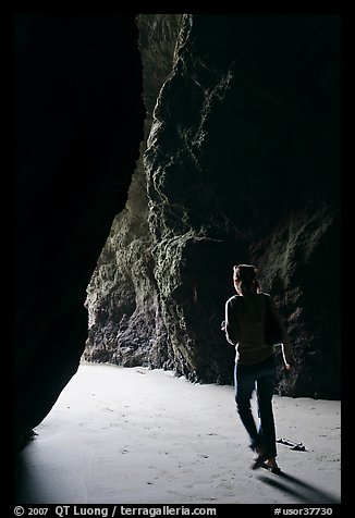 Woman walking out of sea cave. Bandon, Oregon, USA