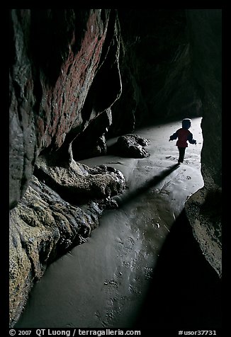 Infant walking out of sea cave. Bandon, Oregon, USA (color)