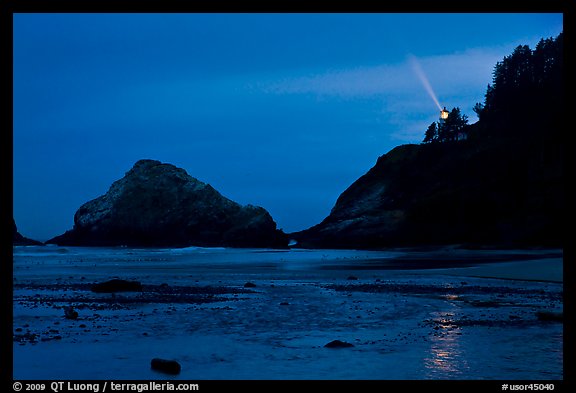 Heceta Head and lighthouse beam from beach by night. Oregon, USA