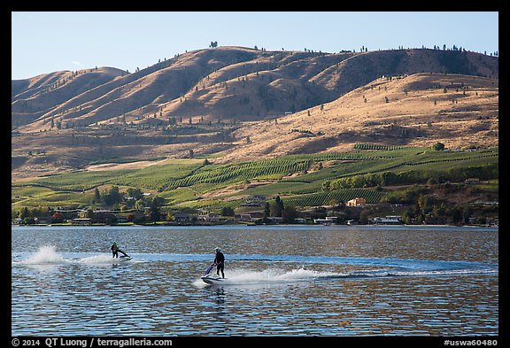 Personal watercraft riders and vineyard covered hills, Lake Chelan. Washington (color)