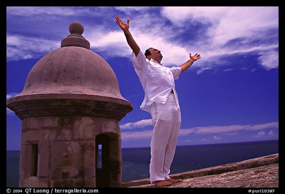 Man standing next to a lookout turret, with arms spread, El Morro Fortress. San Juan, Puerto Rico