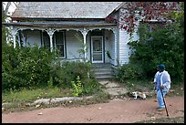 Woman walking dog in front of a crooked house. Selma, Alabama, USA (color)