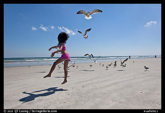 Girl jumping on beach with seagulls flying, Jetty Park. Cape Canaveral, Florida, USA