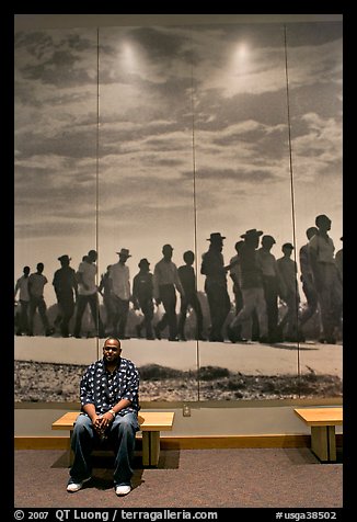 African American man sitting in front of march mural inside Martin Luther King, Jr. Visitor Center. Atlanta, Georgia, USA (color)