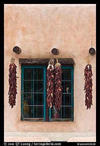Ristras hanging from vigas and blue window. Taos, New Mexico, USA (color)